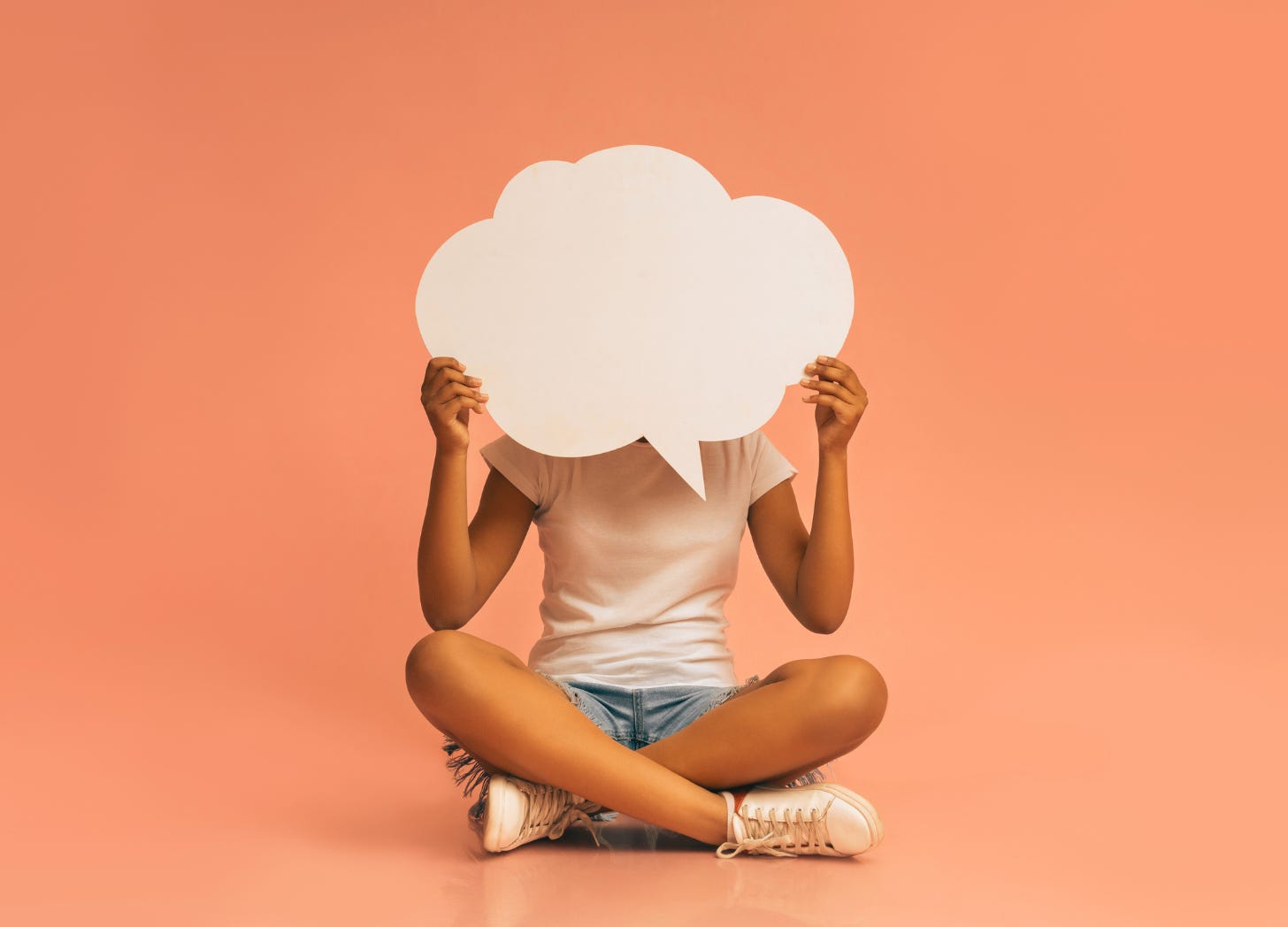 Girl sitting on the floor holding a speech bubble in front of her face signaling she has things to say if only her parent would ask.