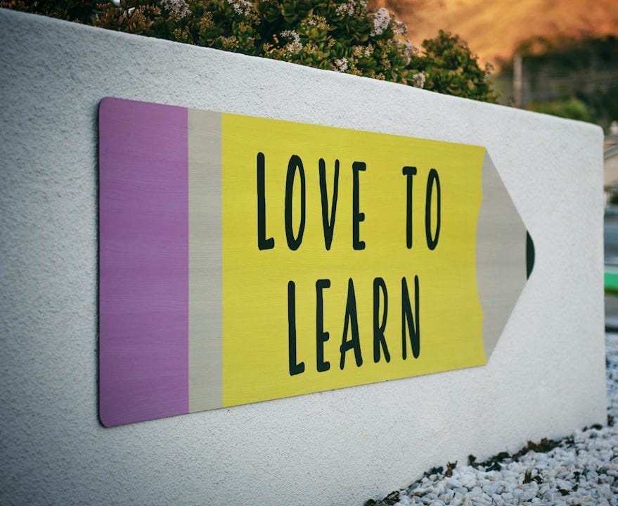 love to learn pencil signage on wall near walking man