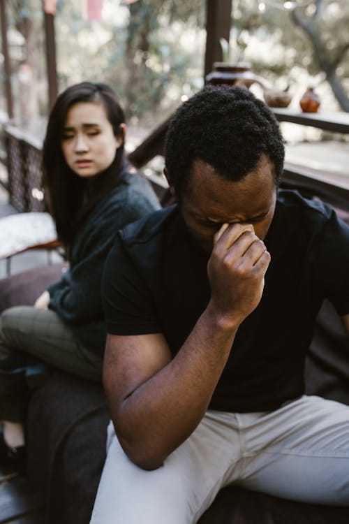 Free A man and woman sit apart, capturing a powerful moment of grief and reflection. Stock Photo
