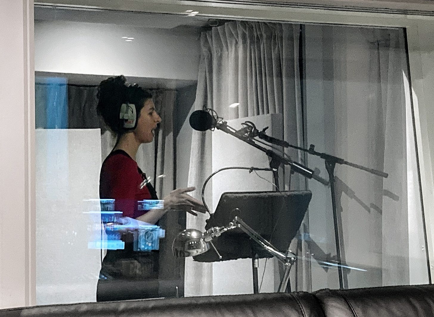 Danielle of Bird Flies Free, wearing headphones and singing into a microphone at a recording studio. Danielle of Bird Flies Free, wearing headphones and singing into a microphone at a recording studio.