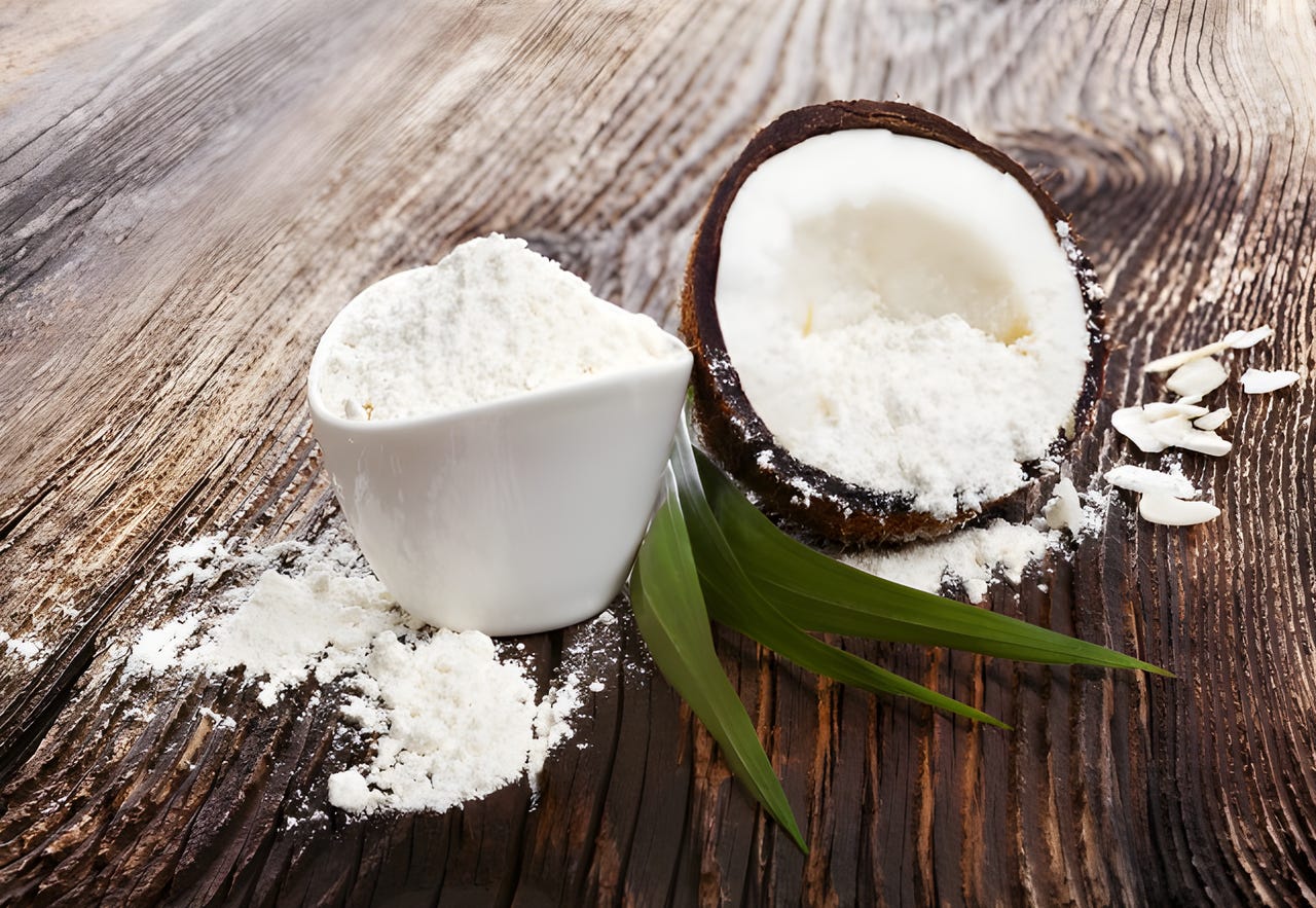 Coconut and a bowl of coconut flour sitting on a wooden table Coconut and a bowl of coconut flour sitting on a wooden table