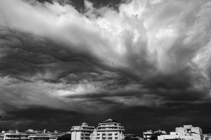 Dramatic black-and-white clouds from below and a couple building at bottom. Dramatic black-and-white clouds from below and a couple building at bottom.