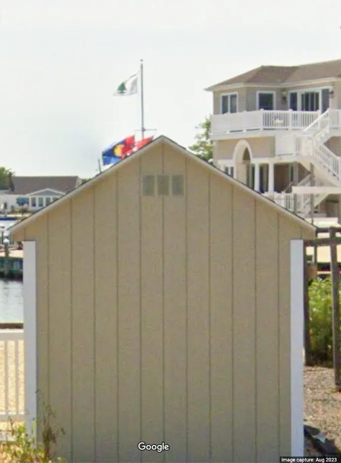 A small shed with a flag pole in the background

Description automatically generated