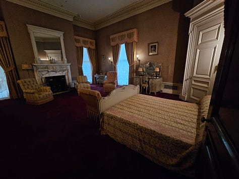 An ornate bedroom with red carpet and gold curtains, and a bathroom with original fixtures.