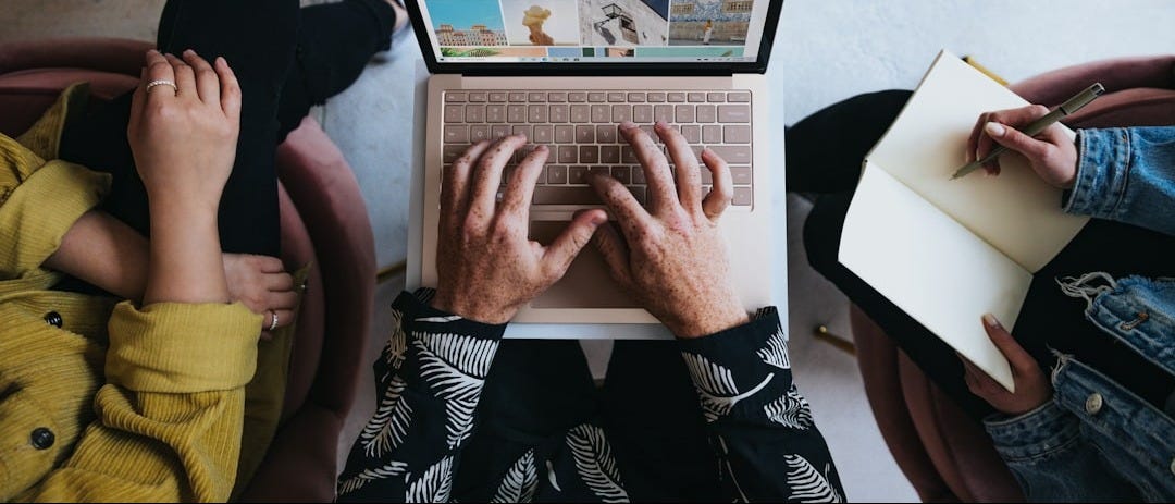 person using microsoft surface laptop on lap with two other people person using microsoft surface laptop on lap with two other people