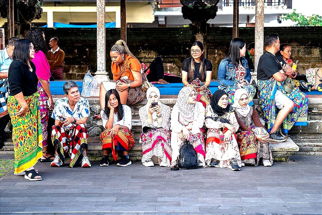 A group of people sitting on a bench next to each other