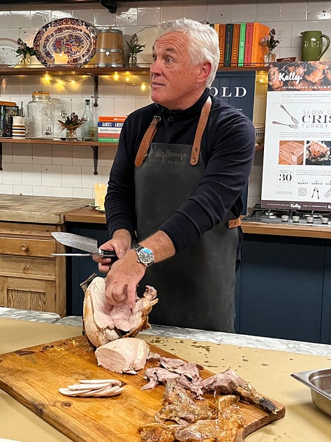 Paul Kelly of the Kelly Bronze company, standing behind a counter demonstrating carving technique.