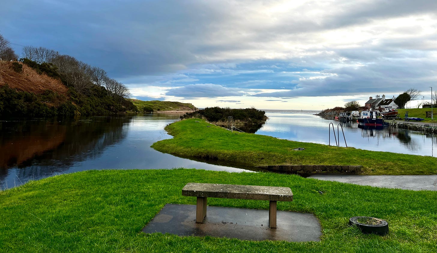 empty stone bench beside two rivers leading to the sea