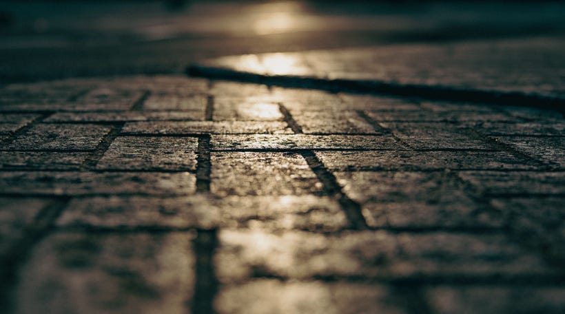 A closeup of the gray brick-style cobblestones common in the Boston area, with a low beam of sun giving shine to the center of the image. A closeup of the gray brick-style cobblestones common in the Boston area, with a low beam of sun giving shine to the center of the image.