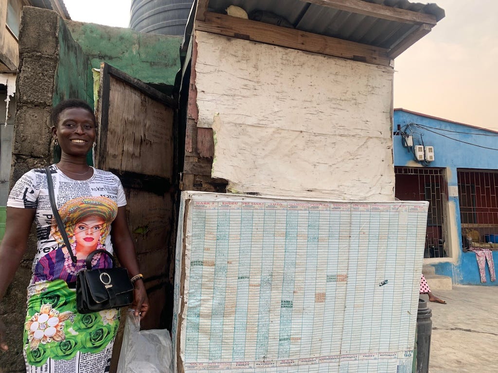 Iya Ibeji Lotto stands next to her kiosk in Kokumo.