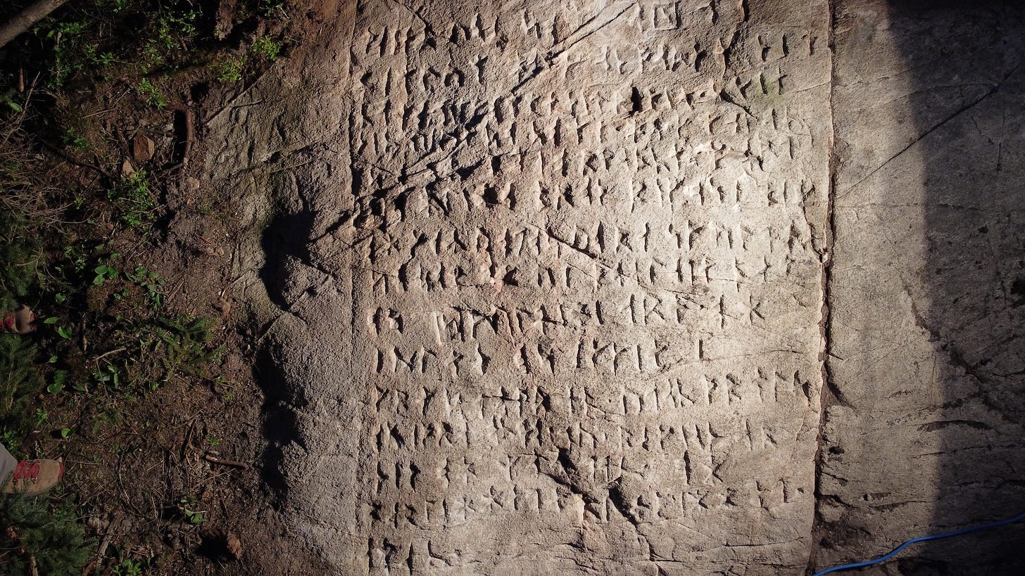 Nordic runes etched into stone slab illuminated by flashlight