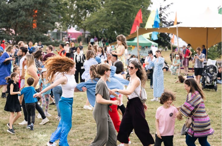 People dancing in a field at a festival People dancing in a field at a festival