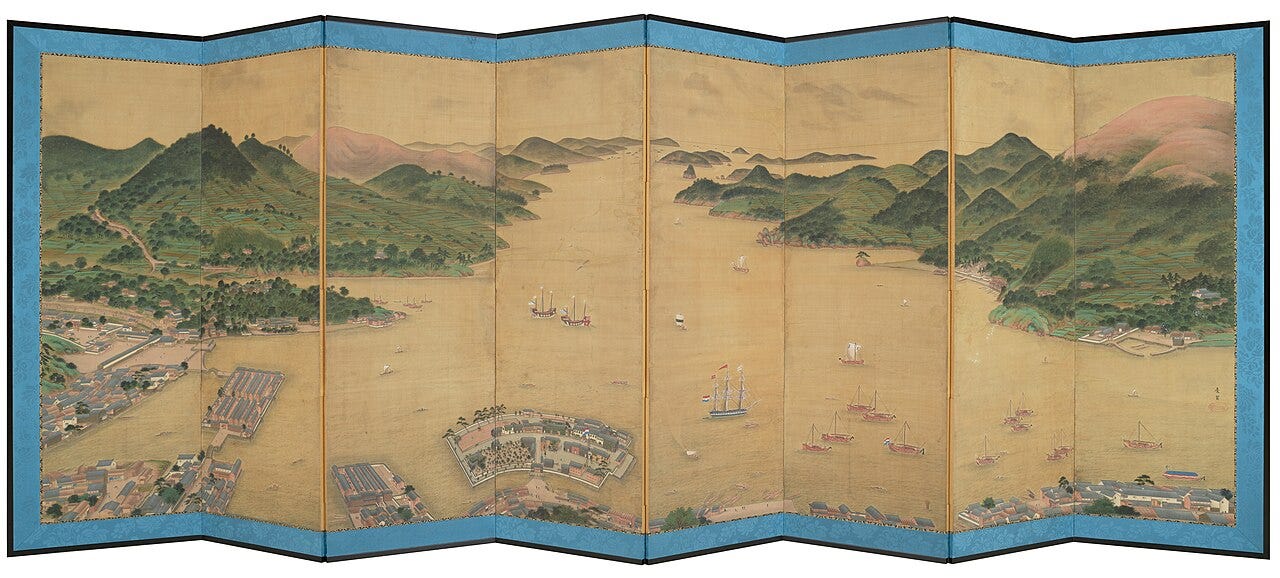 An eight panel folding screen showing the whole of Nagasaki Bay from above, with green hills around the water and the small fan shaped island of Deshima in the foreground