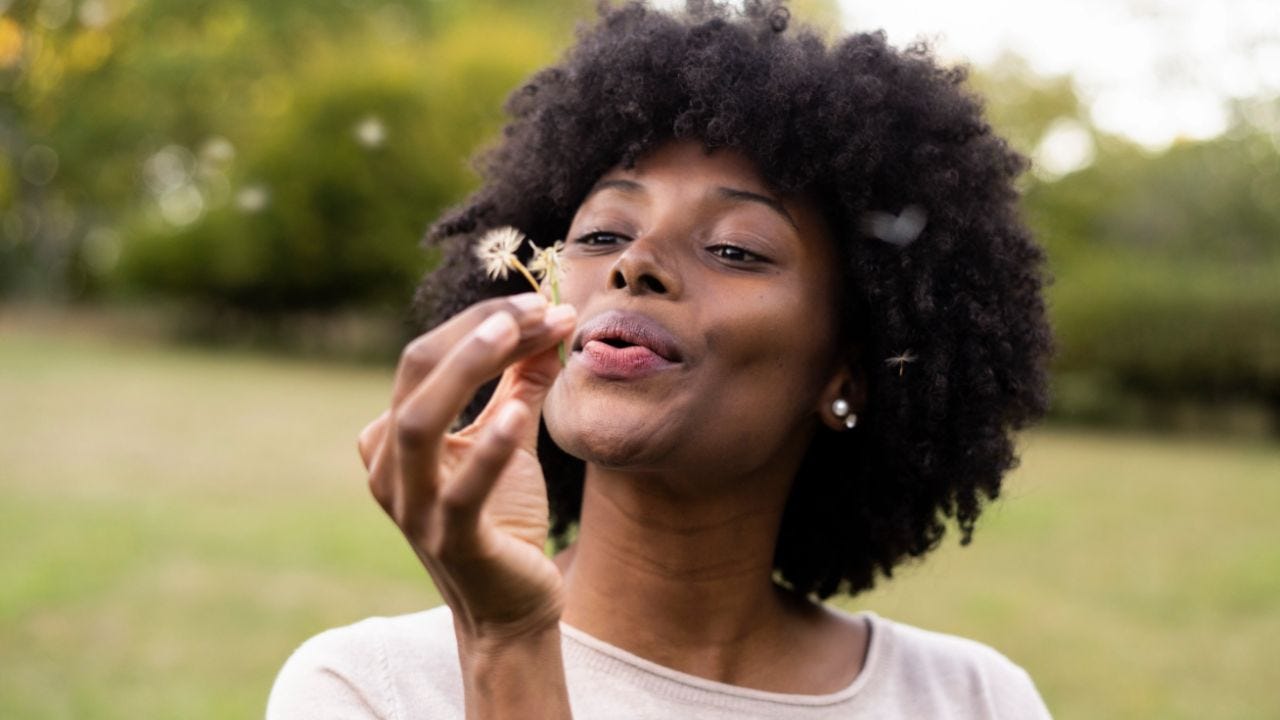 woman blowing on dandelion