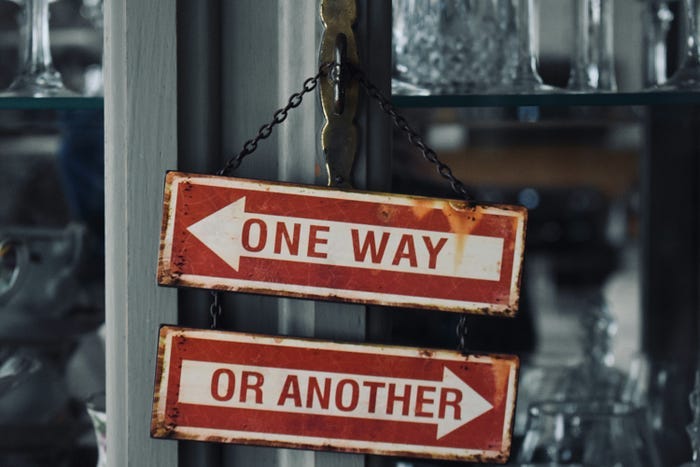 A sign post with two arrows pointing in different directions. One says “One Way”, the other says “Or Another”