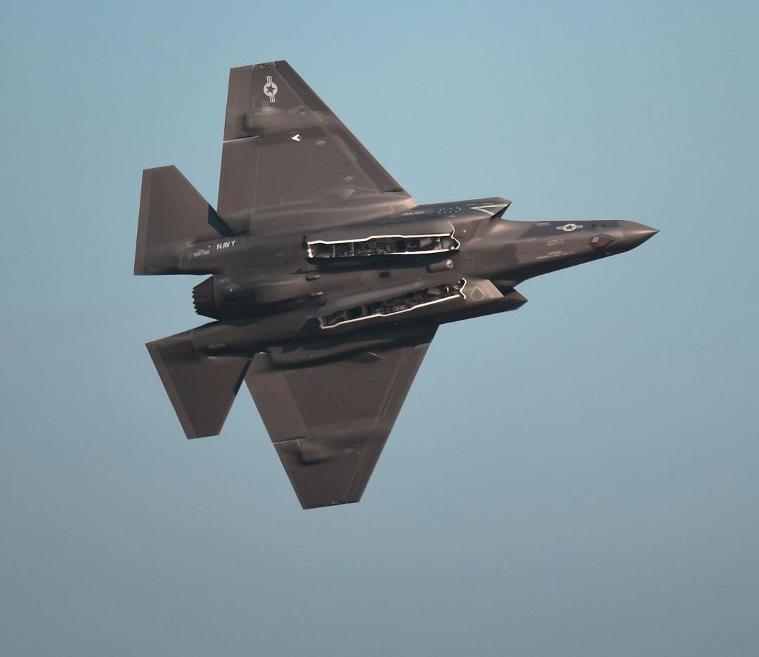 a fighter jet flying through a blue sky a fighter jet flying through a blue sky