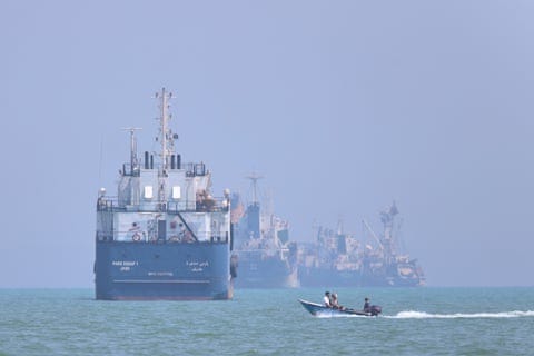 A motorboat passes large ships anchored in the Strait of Hormuz A motorboat passes large ships anchored in the Strait of Hormuz