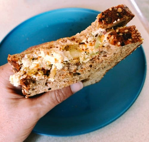 tofu salad sandwich with a blue plate in the background.