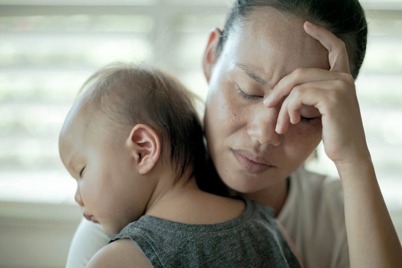 A depressed worried woman at home holding her baby. 
