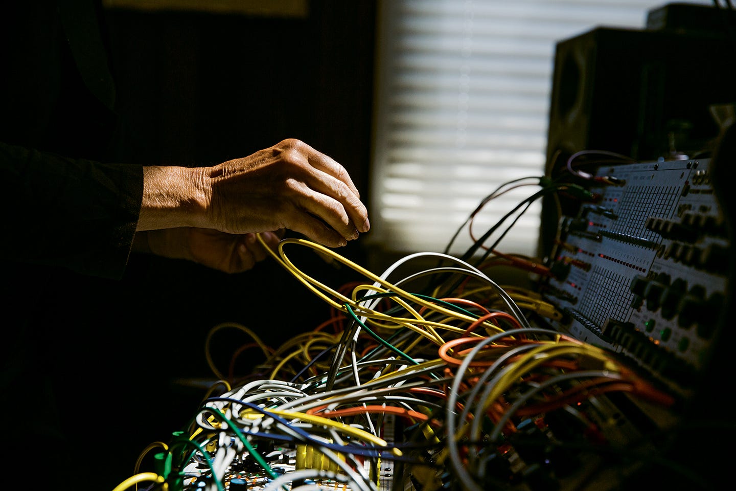 Suzanne Ciani extends in dramatic lighting toward one of her synthesizers.