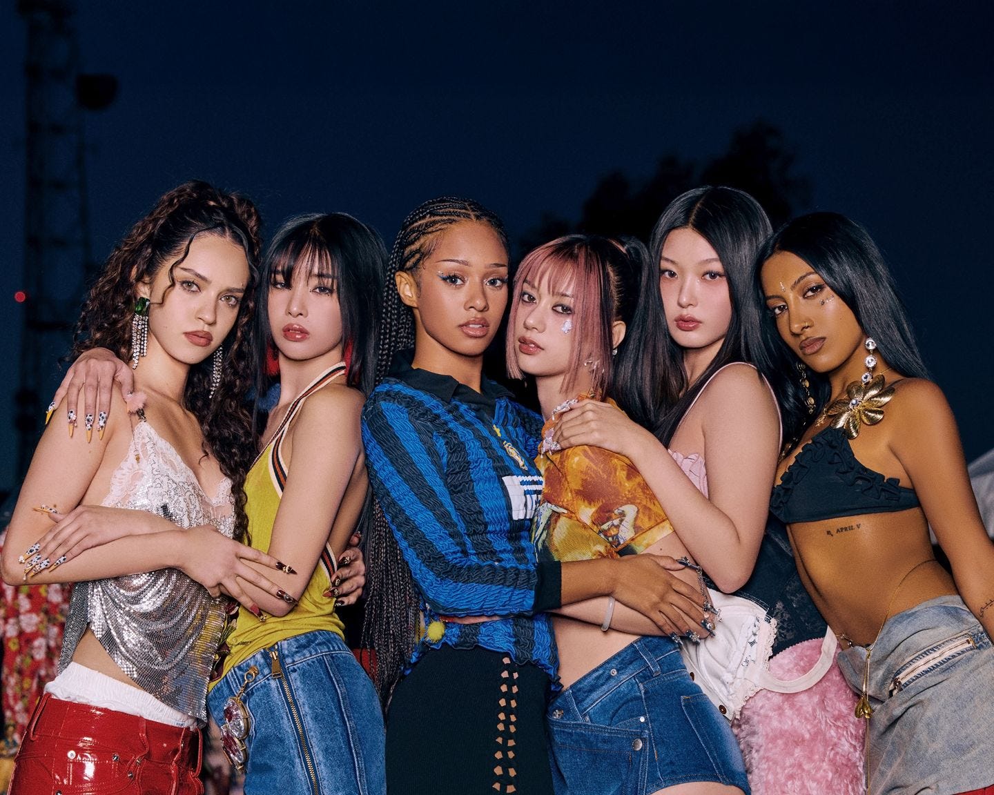 A picture of the six young women of KATSEYE posing in a line. They are holding each other.