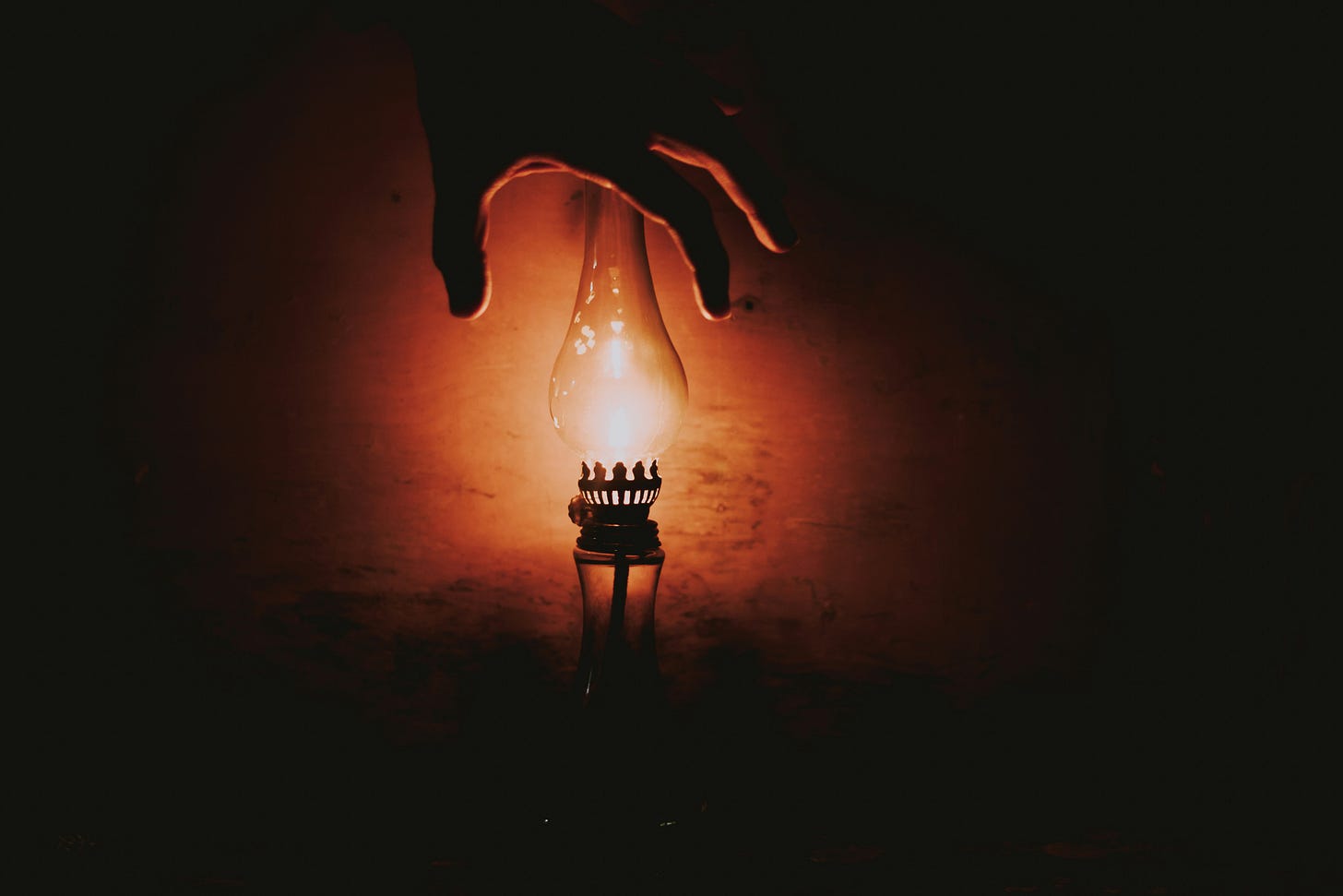 a hand reaching for a light bulb in the dark a hand reaching for a light bulb in the dark