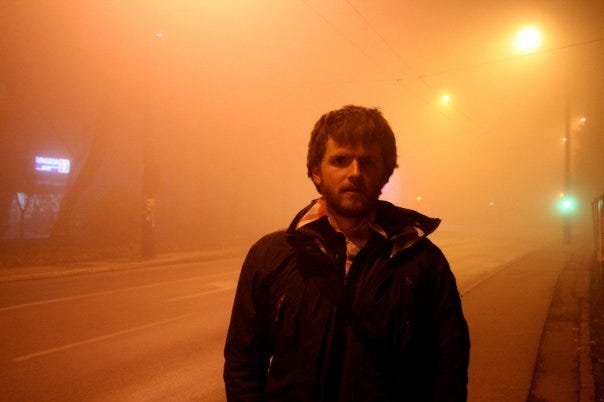 Garrett in a foggy city street full of orange light