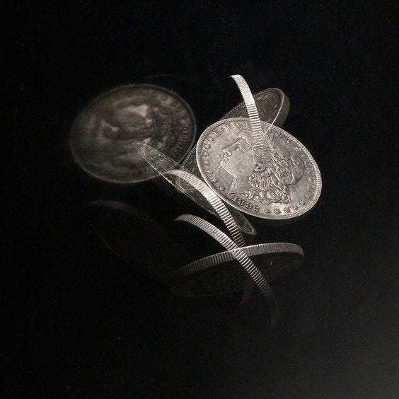 This may contain: two silver coins with ribbons on them sitting next to each other in front of a black background