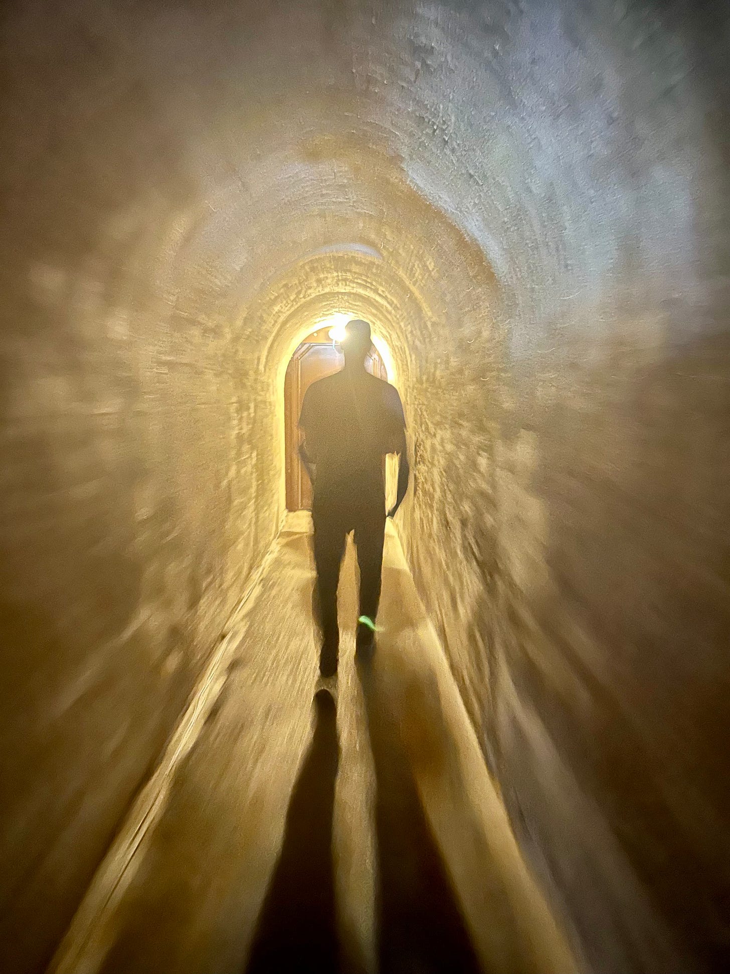 Silhouette of a person walking toward a light at the end of a tunnel