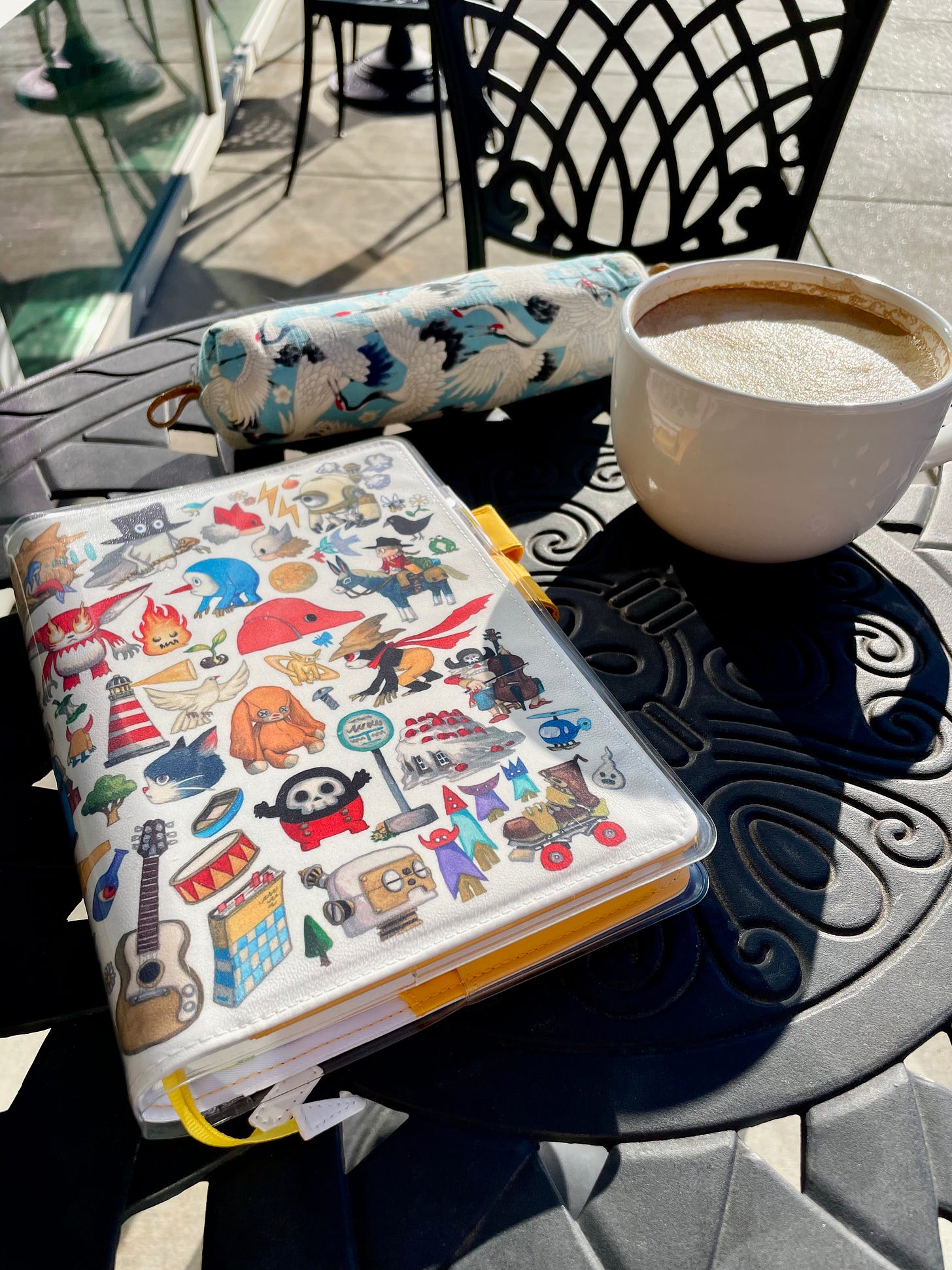 a photo of a planner, a pencil case, and a latter sitting on a black iron cafe table