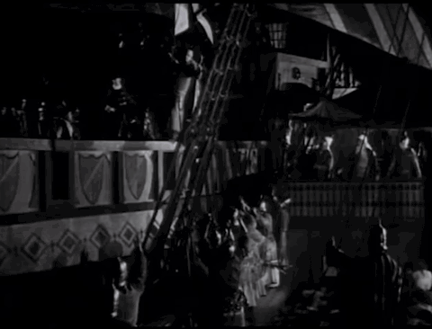 Animated gif - Sir Oliver Tressilian, the Seahawk, is taken away on a British warship. His former crew salute him. Two great ships move alongside each other in the dark