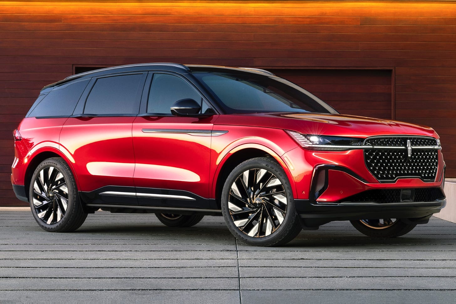 A red 2024 Lincoln Nautilus is parked in the driveway of a luxury home.