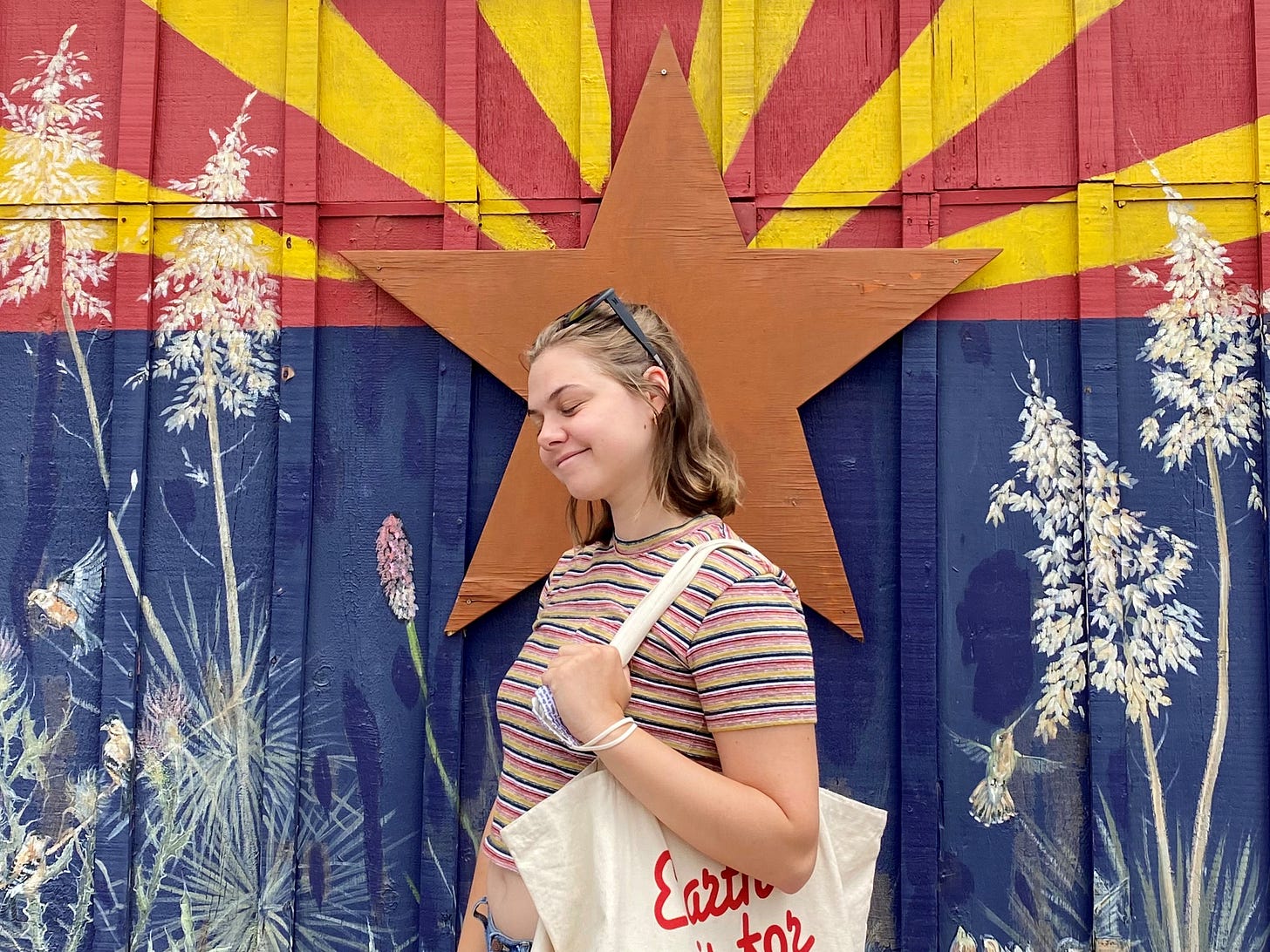 Julianna standing in front of a mural showing off her short new hair.