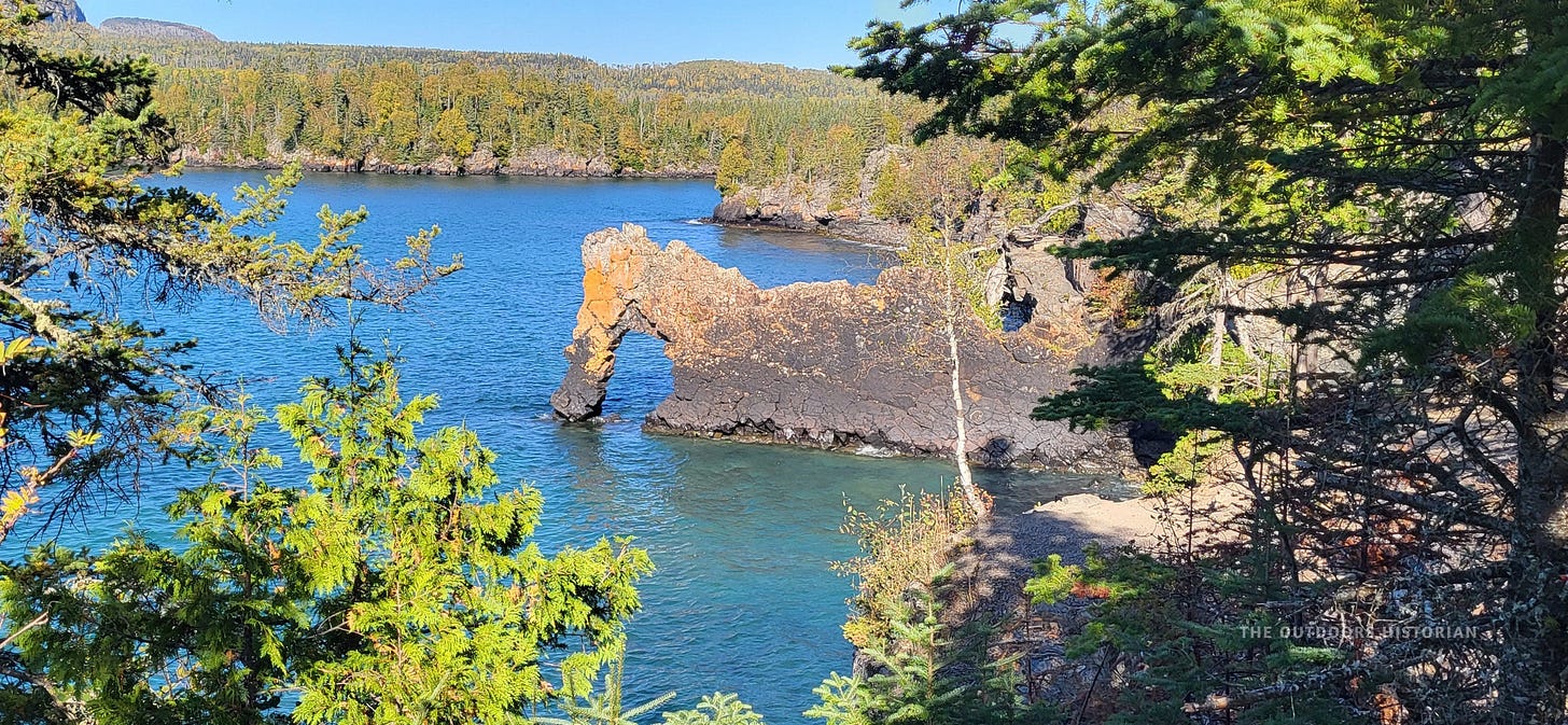 A distinctive rock formation jutting out into turquoise water. It has a natural archway and resembles a seated lion, though the rock is weathered and textured.