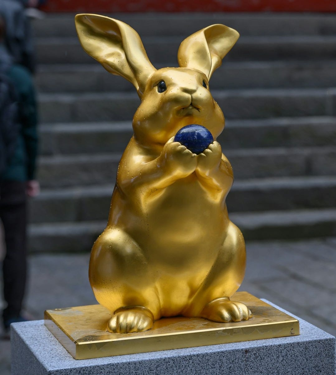 A golden statue of a rabbit on a pedestal with lapis lazuli crystal