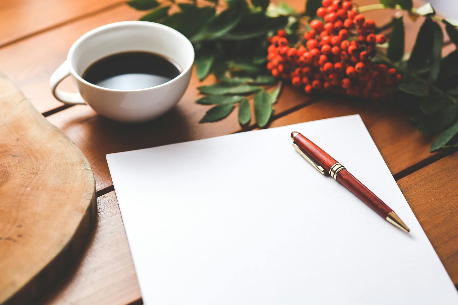 Picture of a cup of coffee next to a blank piece of paper and red pen.