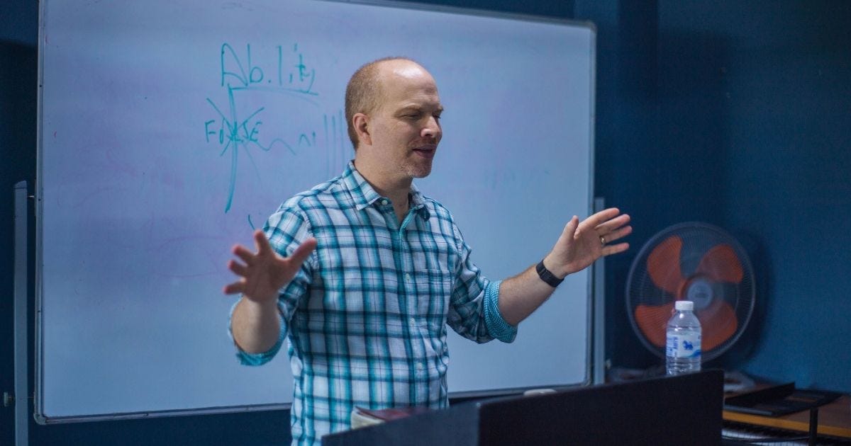 Man passionately explains concepts on a whiteboard in a classroom setting Man passionately explains concepts on a whiteboard in a classroom setting