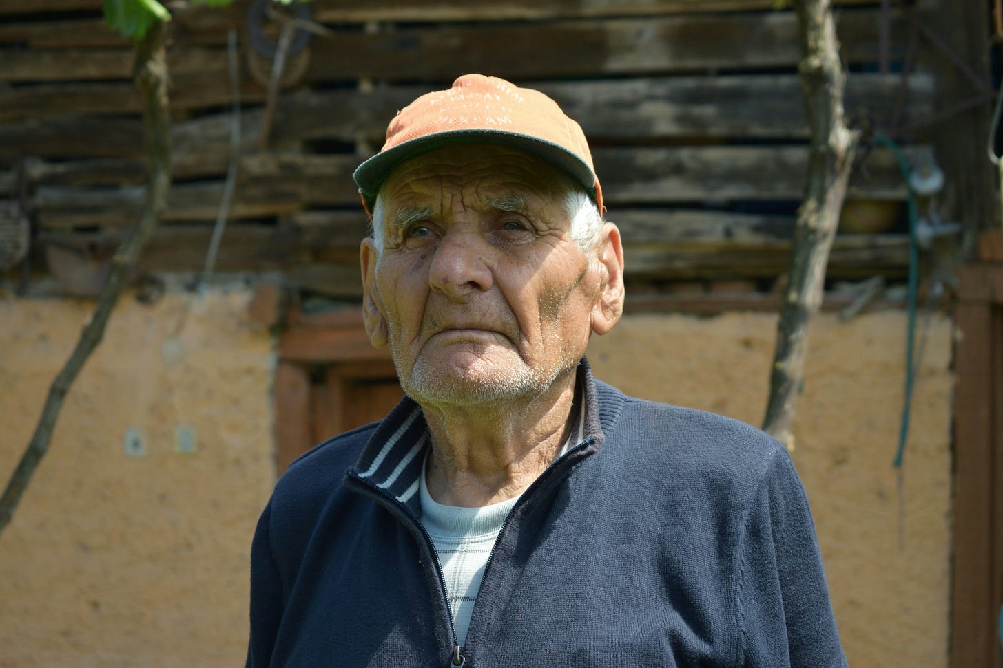 An old man wearing a cap. He looks serious.
