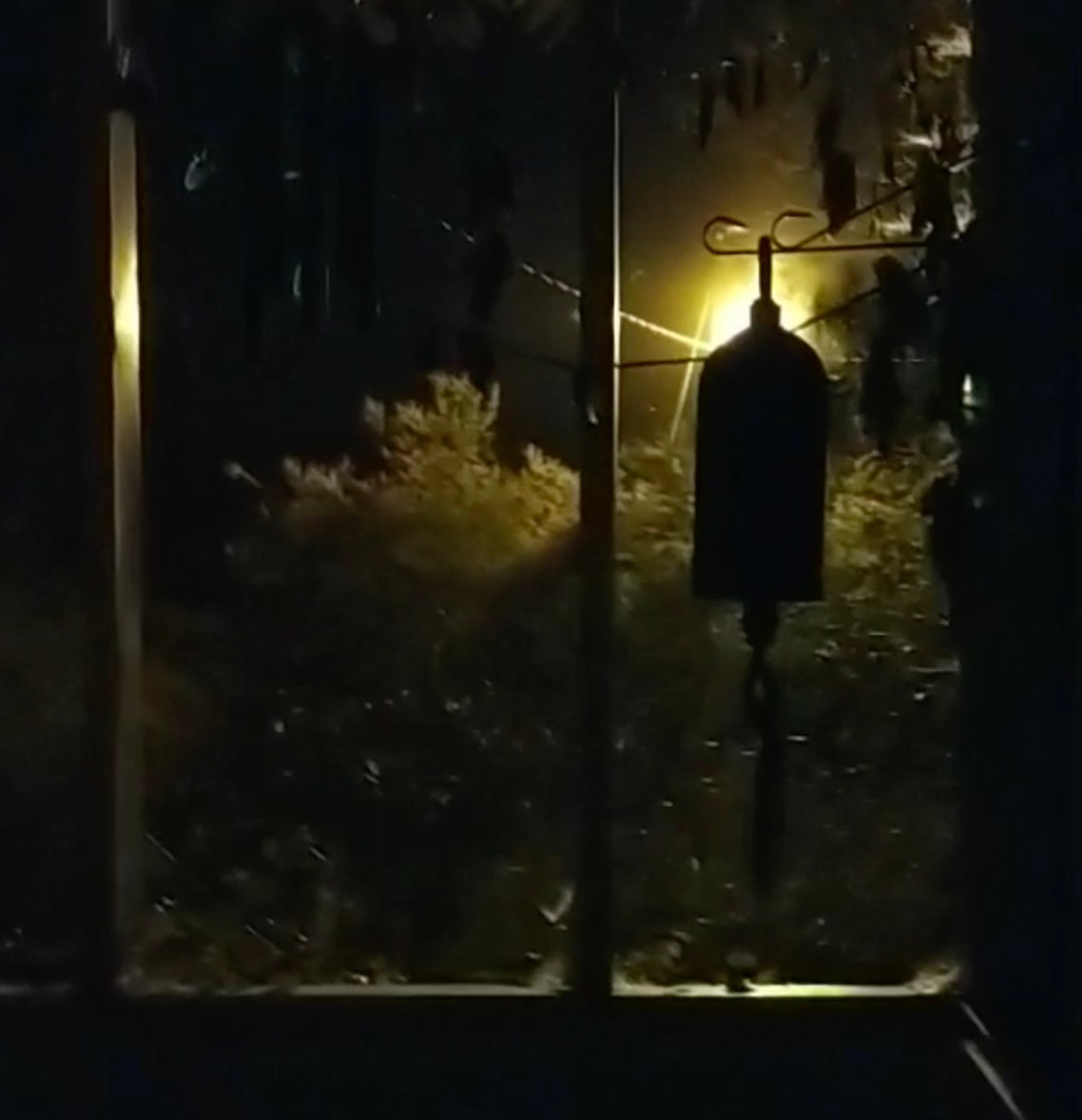 At night, a bell is backlit on a porch