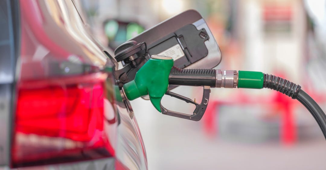 a gas pump is connected to a car at a gas station a gas pump is connected to a car at a gas station