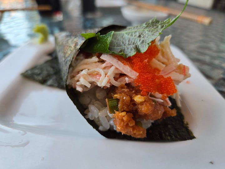 Closeup on the tops of hand rolls, their fillings peeking out over the rice.