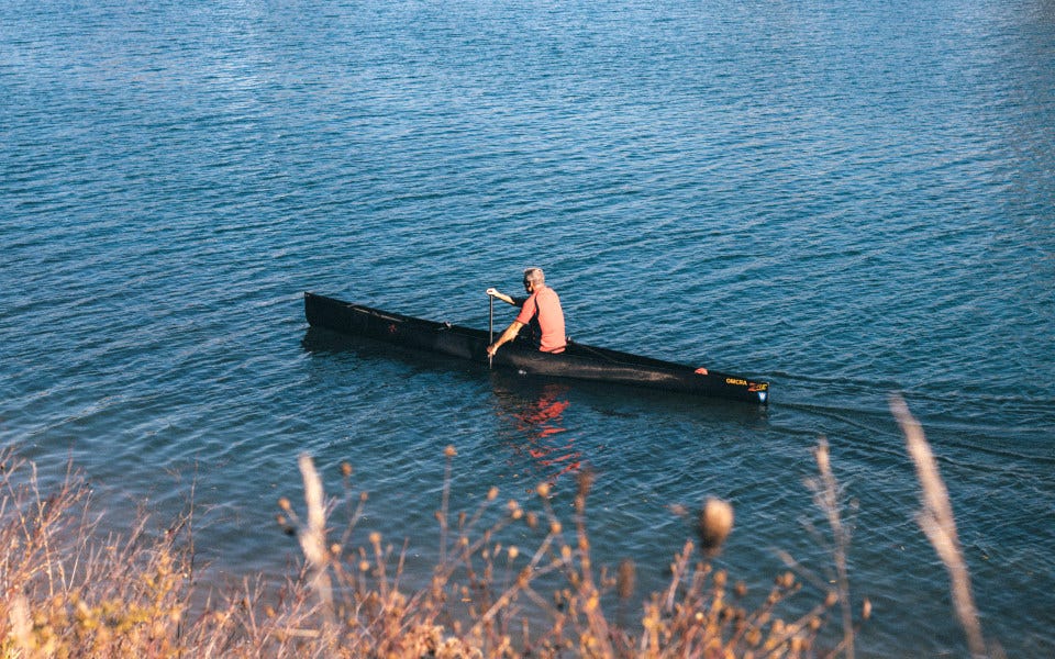 Homme dans canoë glissant lentement sur l'eau Homme dans canoë glissant lentement sur l'eau