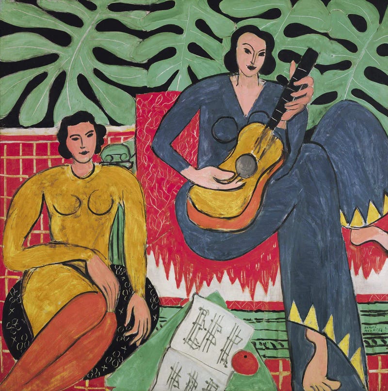 Two women. One is playing guitar. 