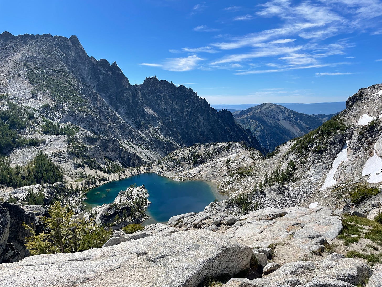 a view of an aquamarine alpine lake framed with mountains and a blue sky