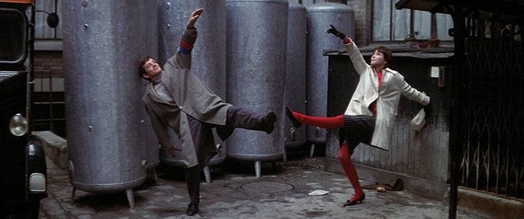This may contain: two people standing in front of metal tanks with their arms up and legs spread out