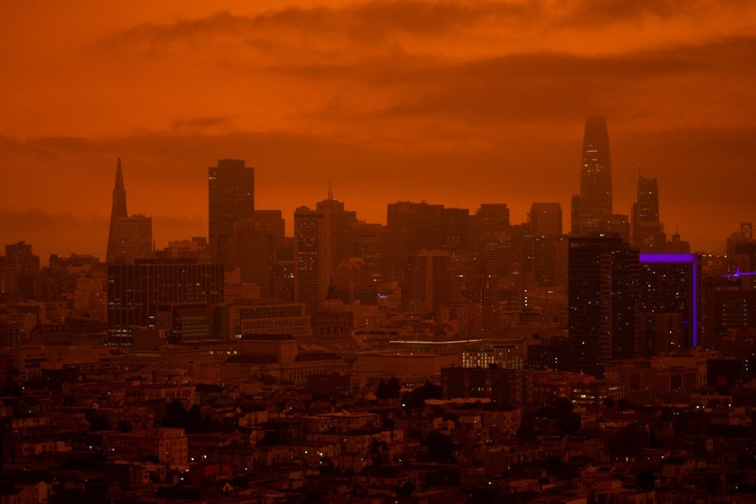 San Francisco city skyline during 2020 labor day fires. The sky is dark orange and buildings are obscured by smoke, even though it's full daylight. San Francisco city skyline during 2020 labor day fires. The sky is dark orange and buildings are obscured by smoke, even though it's full daylight.