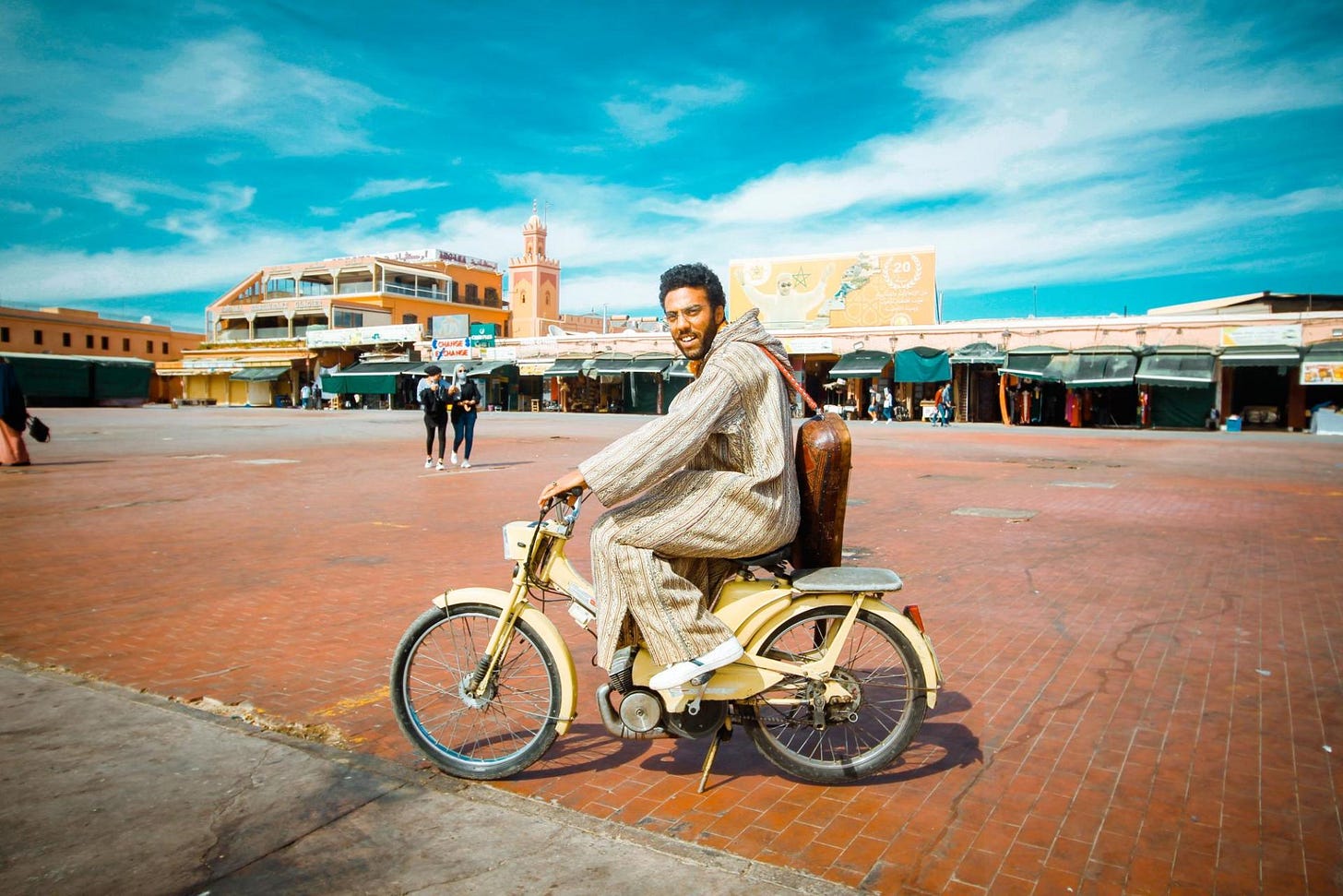 Man in traditional djellaba smiling on a moped in a Moroccan square, photo by Guillermo Martinez Man in traditional djellaba smiling on a moped in a Moroccan square, photo by Guillermo Martinez