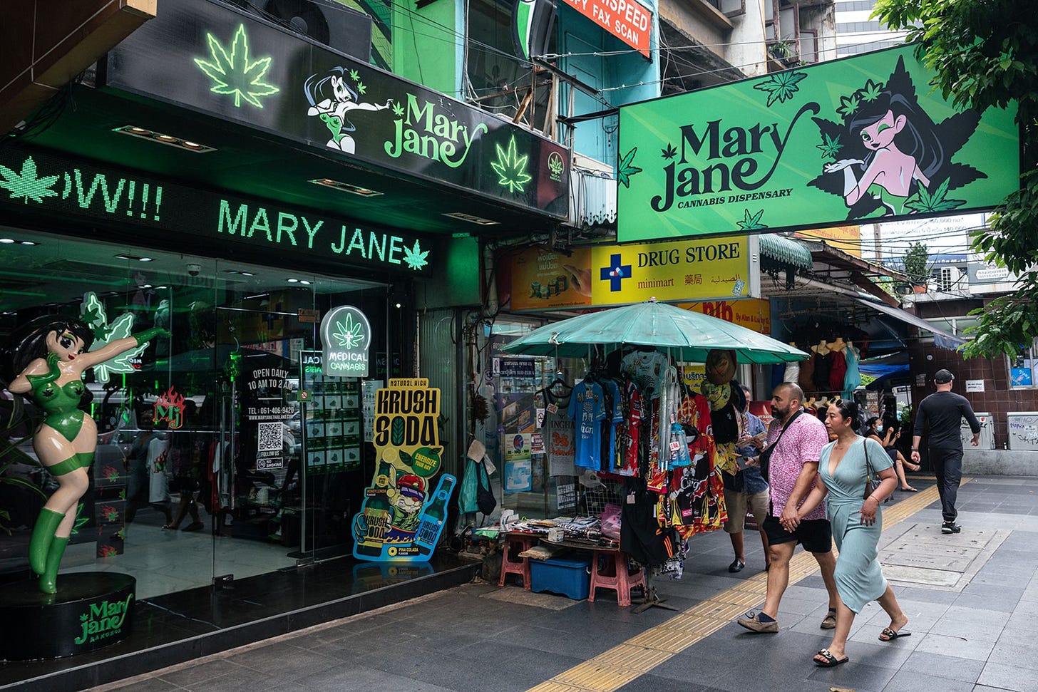 People walk past the Mary Jane cannabis dispensary in Bangkok on May 23, 2025.