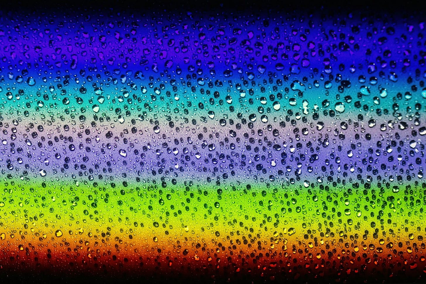 a rainbow of water droplets on a black background