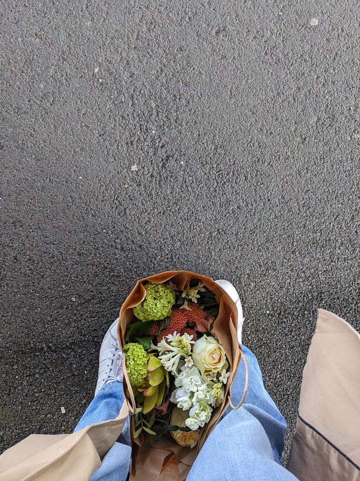 Image one, a brown bag with a bouqet of flowers on the ground between a pair of white trainers. Image two, a image of flowers and dried flowers in a shop.